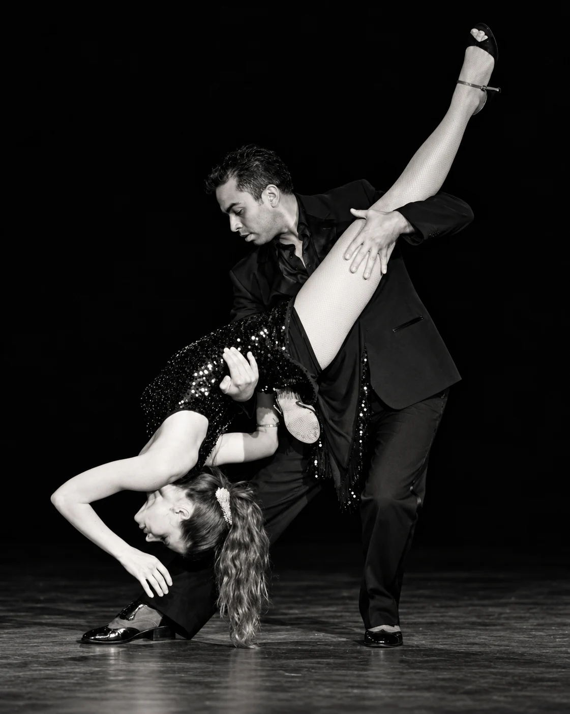 Black-and-white photograph of Daniel supporting his partner in a deep tango dip.